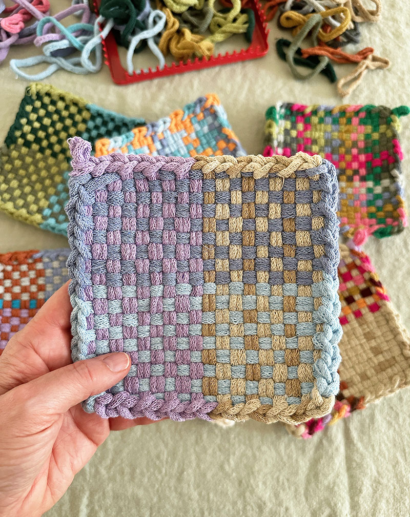 Finished potholder weaving in earthy and purple tones.