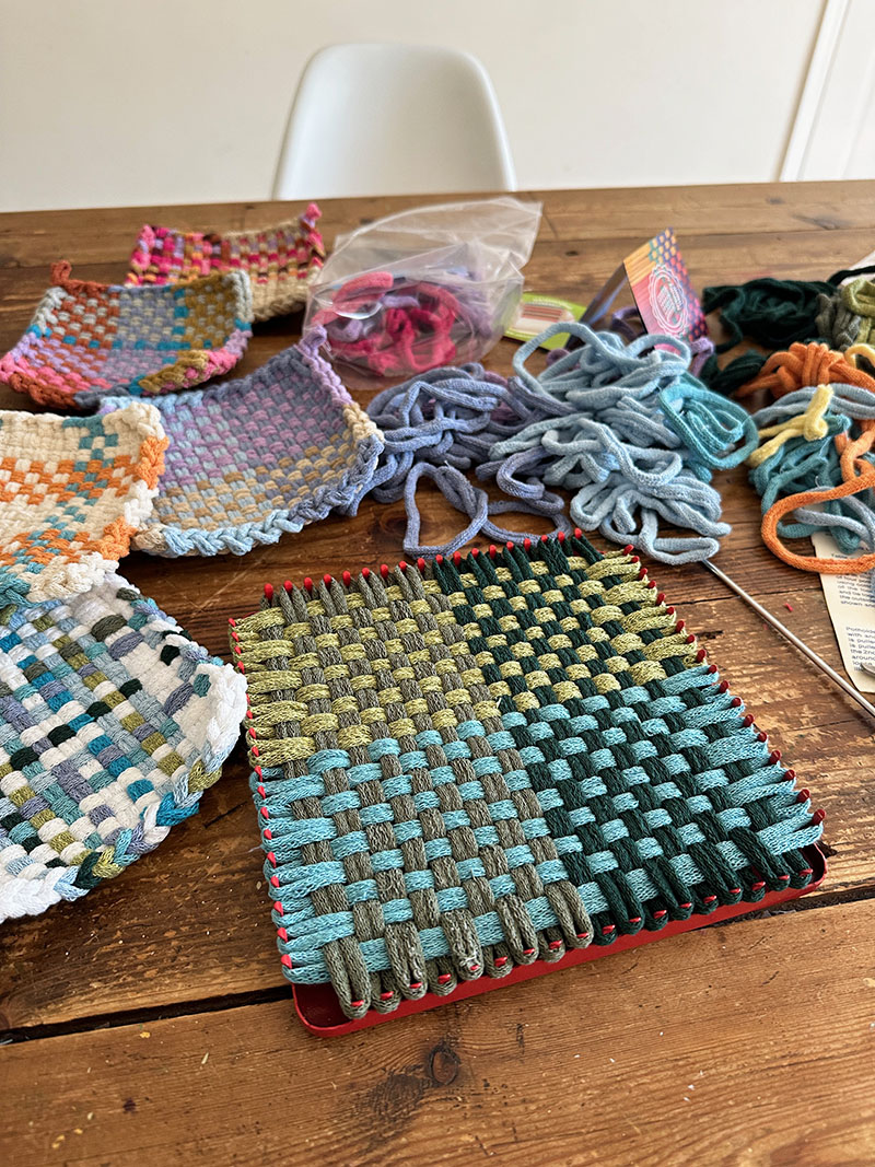A collection of potholders made with Lotta Loops gorgeous colored loops and one potholder still on the loom.