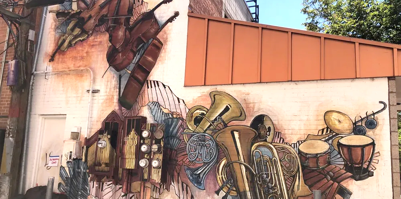 A mural painted in shades of browns and whites representing many different musical instruments.