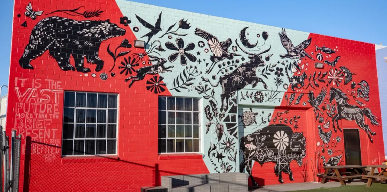 A red and black mural depicting silhouettes of buffalo, bears and horses.