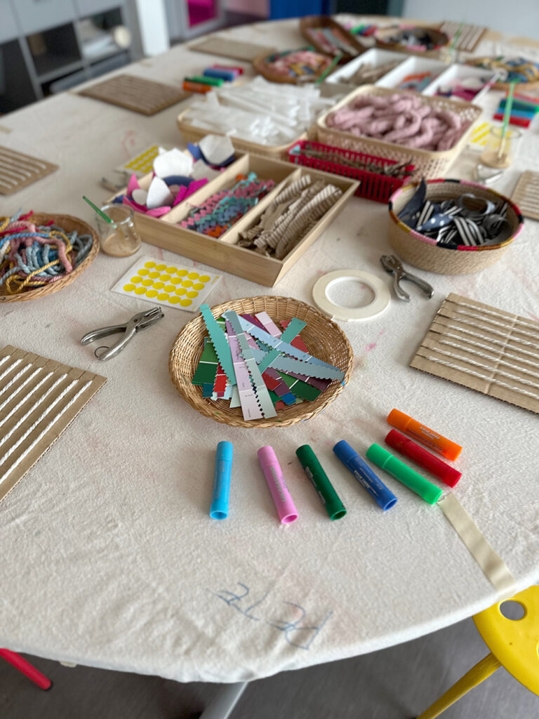 A table set up with cardboard looms and weaving materials ready for children to come and use.