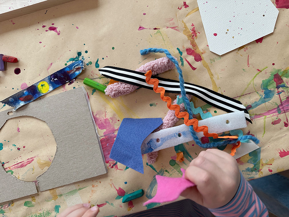 Child with an assortment of weaving materials at a table.