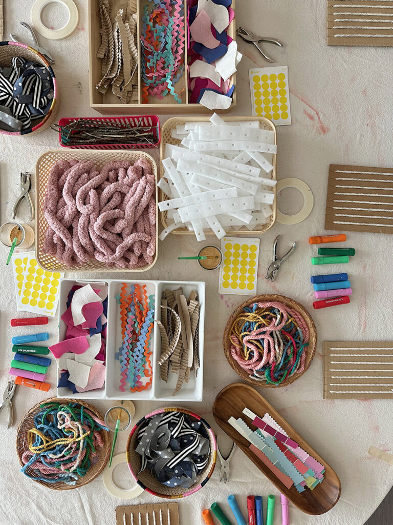 A table set up with cardboard looms and weaving materials ready for children to come and use.